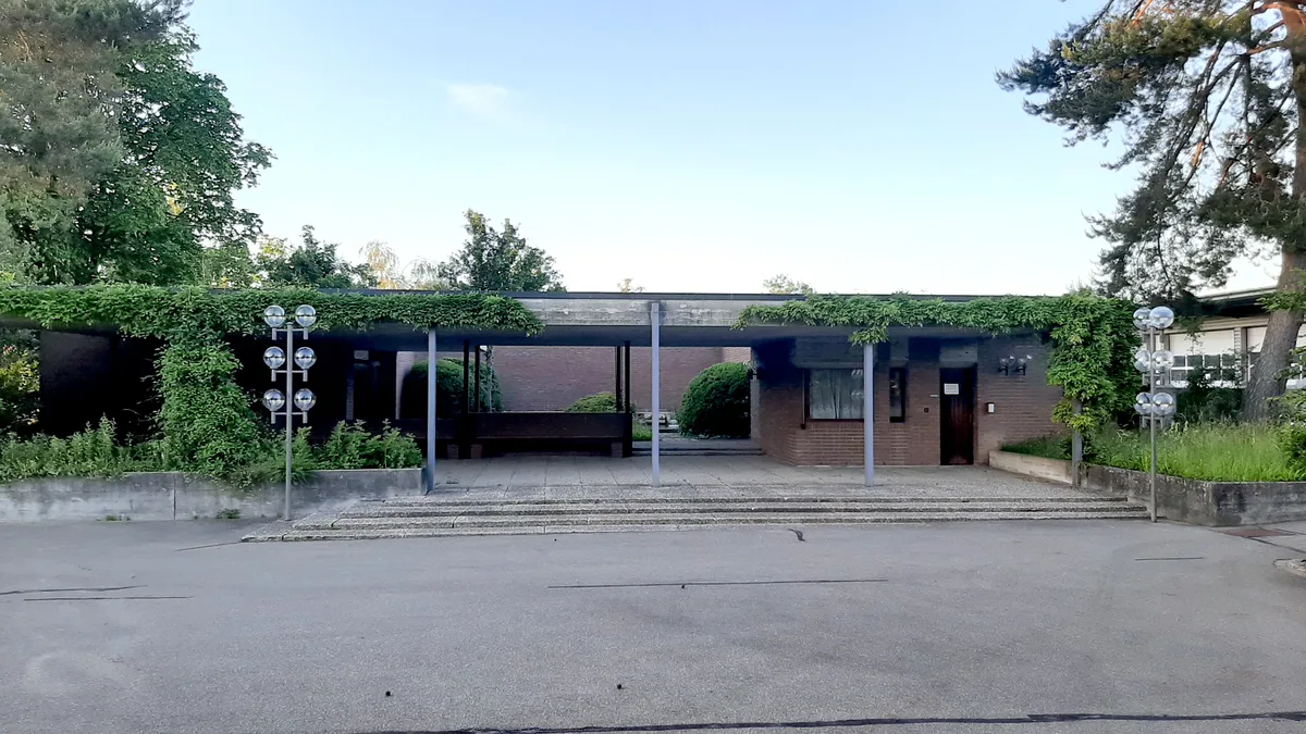 Düsteres Friedhofgebäude mit Sichtbeton und Backsteinmauern.